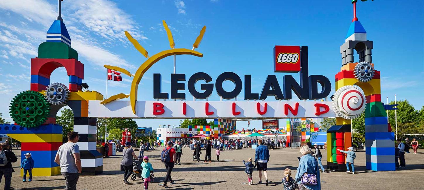 Das Eingangsportal zum LEGOLAND mit den beiden Türmen aus LEGO® Steinen. Viele Gäste kommen, um sich an einem Sommertag mit blauem Himmel zu unterhalten.
