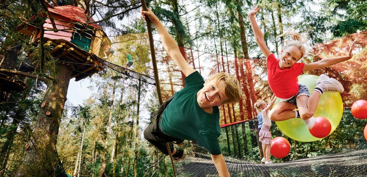 Entdeckt den wunderbaren Wald im WOW Park. Man kann sich, wie dieser Junge, von ganz oben nach unten schwingen. Oder mit Riesenbällen in die gigantisch großen Netze springen.