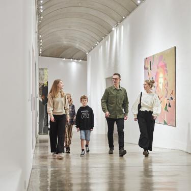 Eine Familie geht den langen Korridor entlang, der mit faszinierenden Kunstwerken gefüllt ist. Sie haben einige der vielen Angebote des Museums für Familien mit Kindern kennengelernt.