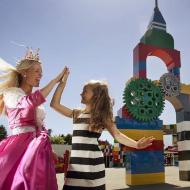 Topattraktion for børn. Prinsesse giver high five til barn foran LEGOLAND® Portalen